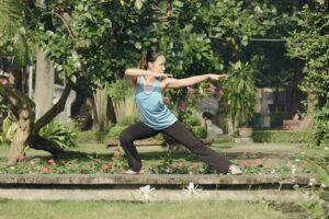Qigong and Christianity - A woman in sports attire practicing qigong surrounded in the park by nature