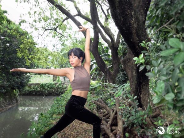A woman practicing Dragon Qigong surrounded by untouched nature