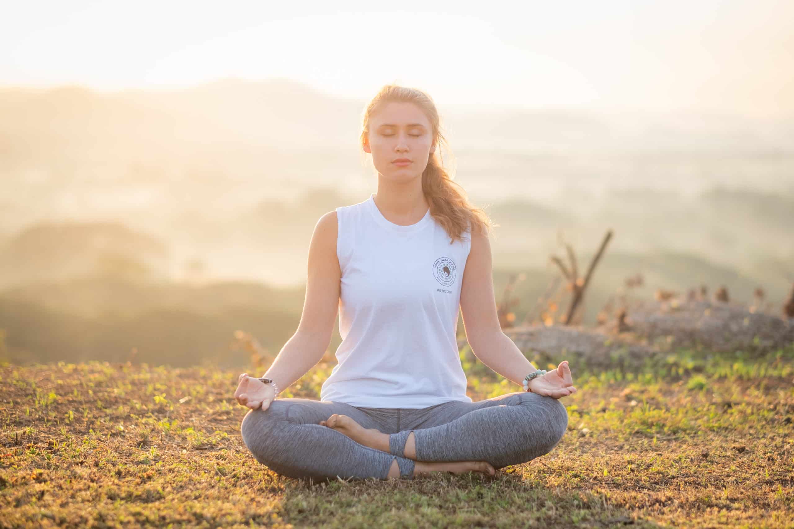 A woman meditating on top of the mountain during sunrise 